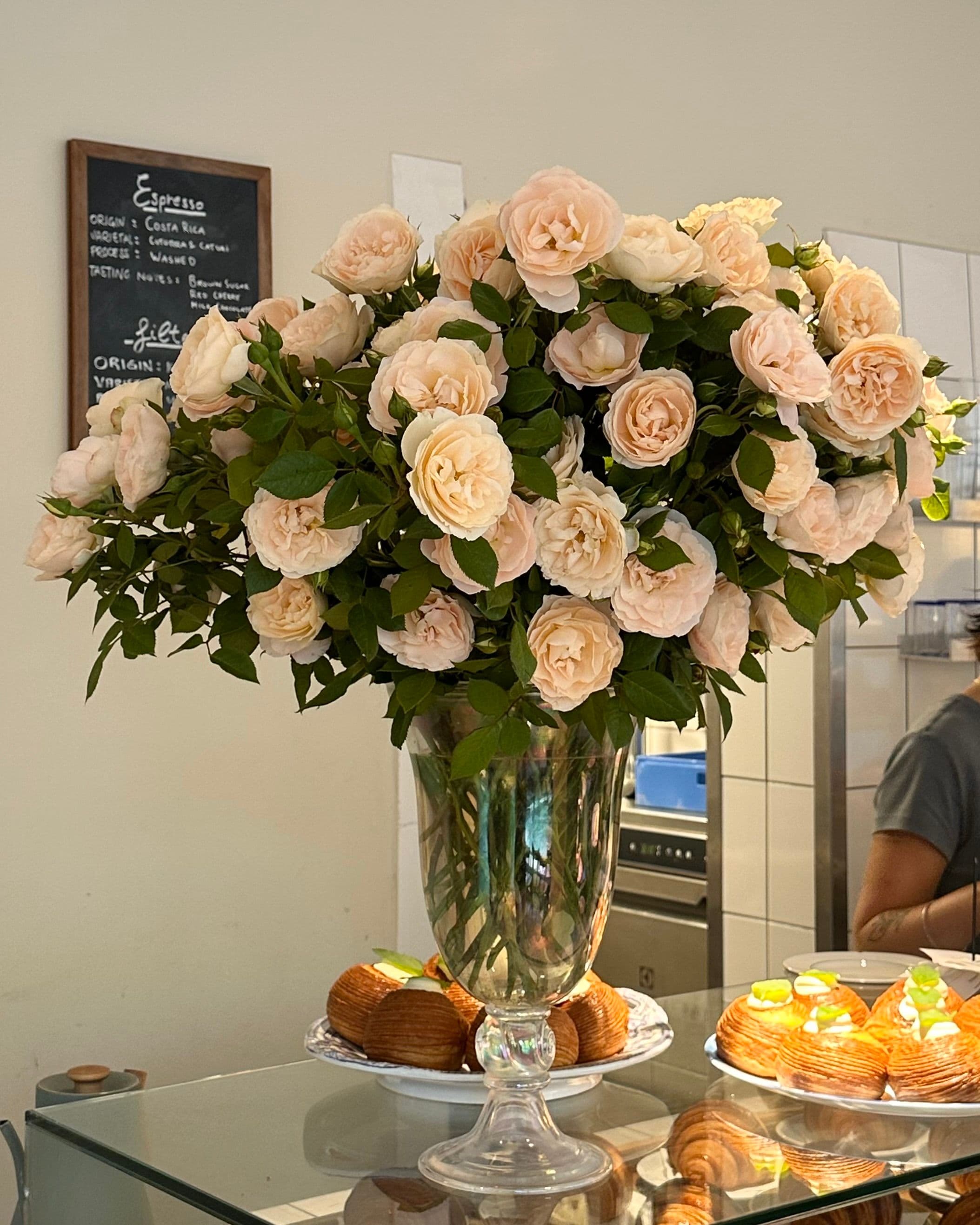 Pale roses in a glass vase on the café counter at Atelier September